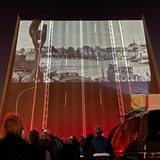 Eine hochgeklappte Straßenbrücke, auf ihr sind Fotos projiziert.