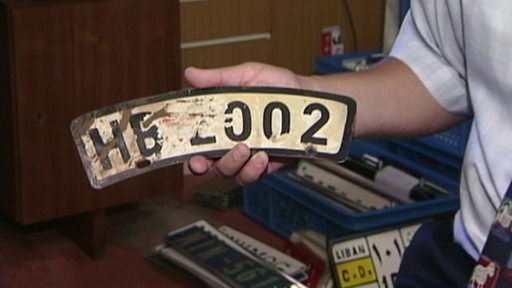 Gebogenes Kraftfahrzeug-Kennzeichen mit der Aufschrift HB 2002