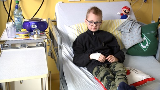Ein Junge liegt in einem Krankenhausbett.