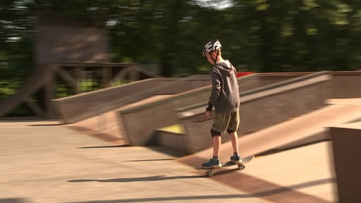 Jugendlicher fährt alleine Skateboard.