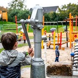 Ein Junge spielt auf einem Spielplatz mit einer Wasserpumpe.