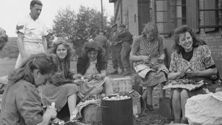 Frauen schälen gemeinsam draußen Kartoffeln