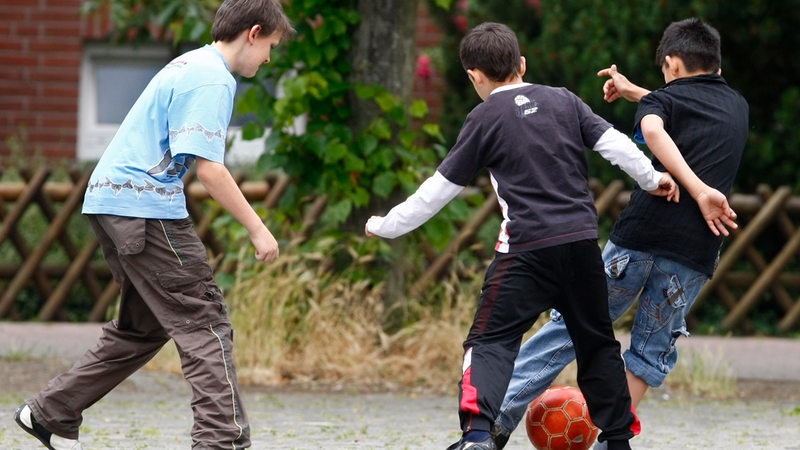Kinder spielen in einer Einfahrt Fußball