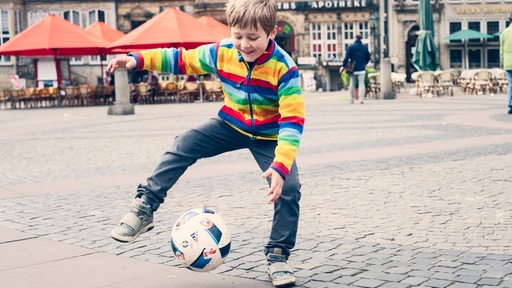 Kleiner Junge spielt Fußball auf Bremer Rathausplatz