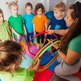 Eine Kindergruppe mit Erzieherin, die Spielreifen verteilt.