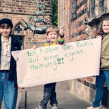 Ein Kind hält ein Schild mit dem Titel: "Ich habe das Recht auf eine eigene Meinung!"
