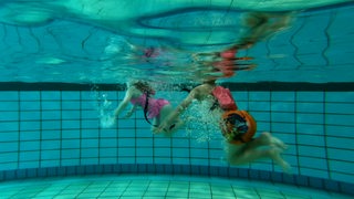 Zwei Kinder in einem Schwimmbecken beim Schwimmkurs.