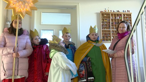 Als heilige Könige verkleidete Kinder singen in einem Haus
