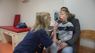 Ein kleiner Junge wird in einer Kinderarzt-Praxis von einer Ärztin untersucht. 