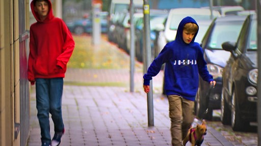 Zwei Jungs auf dem Bürgersteig mit einem Hund.