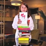 Junge mit Bücherstapel.