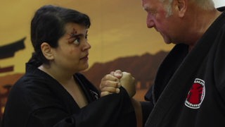 Eine Szene auf dem Kinofilm "Nico" von Sara Fazilat. Eine junge Frau mit Blut im gesicht schaut einem älteren Mann intensiv ins Gesicht und hält seine Hand. 