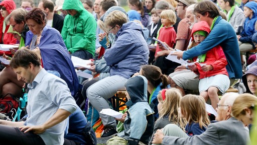 Kinder nehmen mit ihren Vätern und Großvätern an einem Gottesdienst auf dem Deutschen Evangelischen Kirchentag teil.