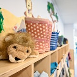 Ein Kuscheltier und Kinderkleidung in der Garderobe einer Kita