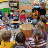 Eine Erzieherin musiziert mit einer Kindergartengruppe