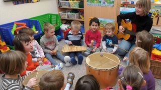 Eine Erzieherin musiziert mit einer Kindergartengruppe