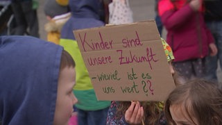 Ein Kind hält ein Schild hoch in der Demo. 