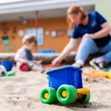 Ein Kind spielt mit einer Erzieherin im Sandkasten einer Kita.