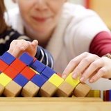 Eine Erzieherin spielt gemeinsam mit einem Kindergartenkind mit Holzspielzeug.