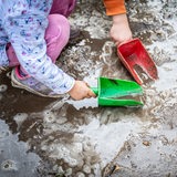 Kinder spielen mit Schaufeln in Sand und Matsch