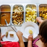 Kinder befüllen ihre Teller beim Mittagessen in einer Kita