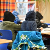 Schülerinnen und Schüler arbeiten im Klassenzimmer in warmer Kleidung.