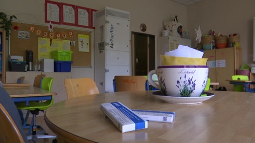 Zwei Corona-Schnelltests liegen auf einem Tisch in einem Klassenzimmer.