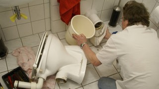 Ein Klempner repariert eine Toilette.
