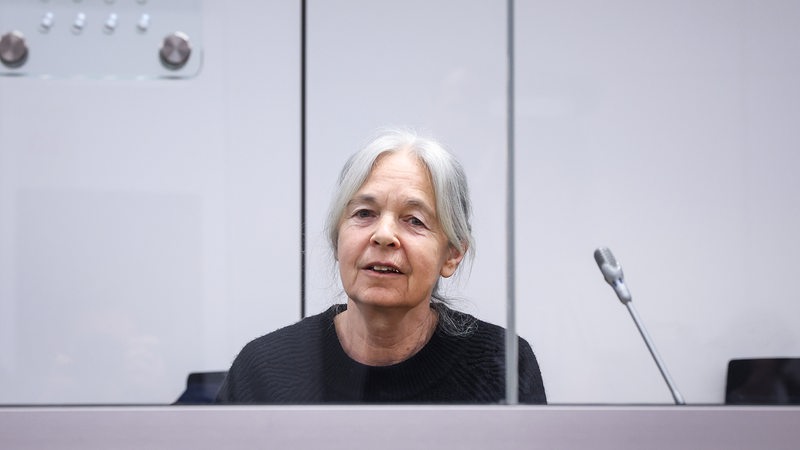 Daniela Klette sitzt lächelnd im Oberlandesgericht Celle im Gerichtssaal auf der Anklagebank. 