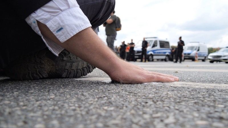 Ein Klimaaktivist hat sich mit der Handfläche am Asphalt einer Straße in der Bremer Innenstadt festgeklebt. 