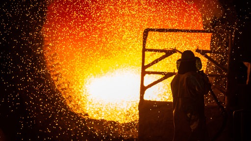 Ein Mitarbeiter reinigt im Stahlwerk eine Roheisenpfanne. 
