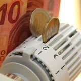An einem Heizungsthermometer sind ein Geldschein und zwei Euro-Münzen