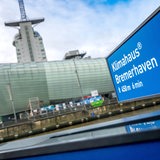 Ein Wegweise steht vor einem im Hintergrund verschwommenem Gebäude.