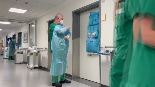 Ein Arzt im Klinikum Bremen-Mitte zieht sich Arbeitskleidung an.