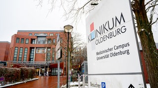 Im Hintergrund ist ein Gebäude zu sehen. Im Vordergrund sieht man das Schild "Klinikum Oldenburg"