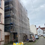 Ein Baugerüst steht vor einem Mehrfamilienhaus.
