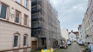 Ein Baugerüst steht vor einem Mehrfamilienhaus.