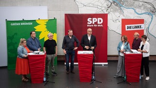 Bremer Vertreter von Grünen, SPD und Linken stehen hinter Rednerpulten.