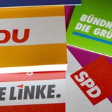 Logos und Broschüren von SPD, CDU, Grüne und Linke liegen aus