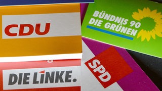 Logos und Broschüren von SPD, CDU, Grüne und Linke liegen aus