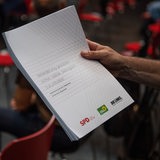 Eine Hand hält den neuen Koalitionsvertrag für Bremen.