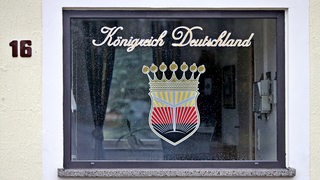 Das Logo des "Königreich Deutschland" prangt am Fenster eines Pförtnerhauses in Lutherstadt Wittenberg (Sachsen-Anhalt).