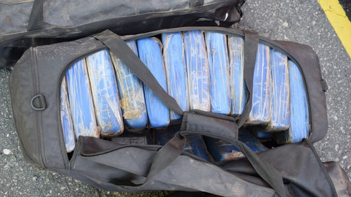 In einer Reisetasche liegen blaue Pakete.
