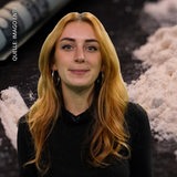 Eine Moderatorin blickt in die Kamera. Im Hintergrund zeigt ein Foto Kokainpulver.