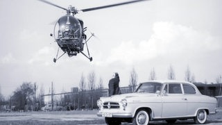 Eine alte Aufnahme zeigt ein Borgward-Auto und einen Hubschrauber des Typs Kolibri.