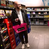 Ein Mann trägt einen pinken Einkaufskorb in einem Supermarkt