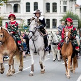Drei kostümierte Reiter auf einer Straße während eines Umzugs
