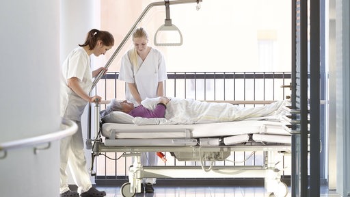 Krankenschwestern schieben einen Patientin durch das Krankenhaus. 