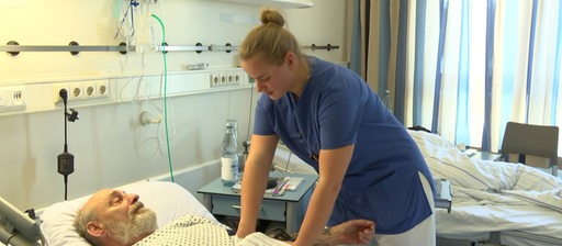 Eine Pflegerin im Krankenhaus am Bett eines Patienten.
