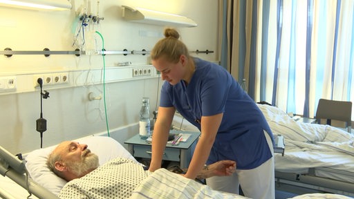 Eine Pflegerin im Krankenhaus am Bett eines Patienten.